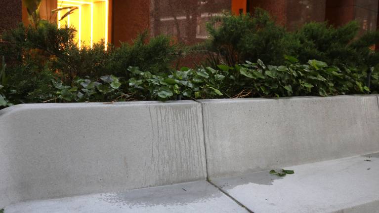 Sprinklers soak the seating when turned on, occasionally spraying pedestrians.