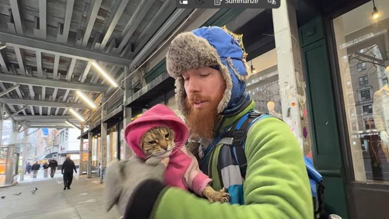 An unhoused individual, Ethan, known locally as “Freckles,” holds his cat “kitty” the day after a city sweep. He says he always returns to the Broadway and W. 75th St. location under a scaffold the minute city officials leave because he prefers to live outside.